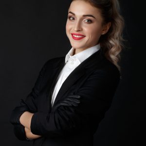 Sexy smart blonde with long curly hair poses in black jacket and Sexy smart blonde with long curly hair poses in black jacket and black gloves in a dark studio